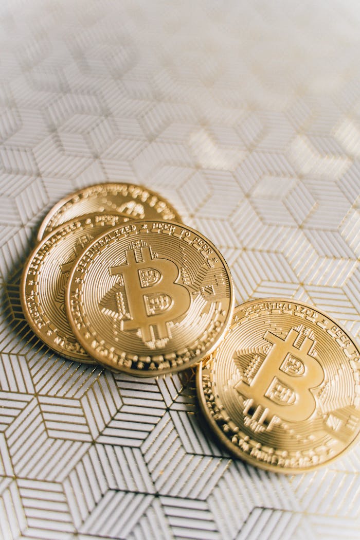 services-03 Close-up of gold Bitcoin coins on a patterned surface, representing digital currency.